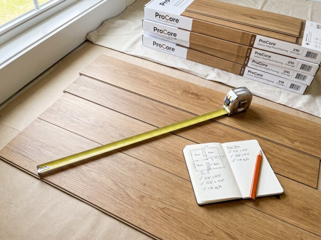 Flat-lay image of DIY vinyl plank flooring project with a tape measure and flooring boxes.